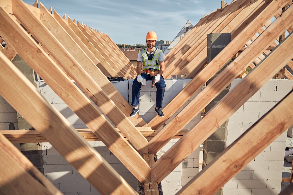 Cheerful male builder holding a drill while sitting